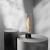 SPIN Air 1200 de Höfats, chimenea de bioetanol de sobremesa negra con diseño cilíndrico y llama giratoria decorativa.